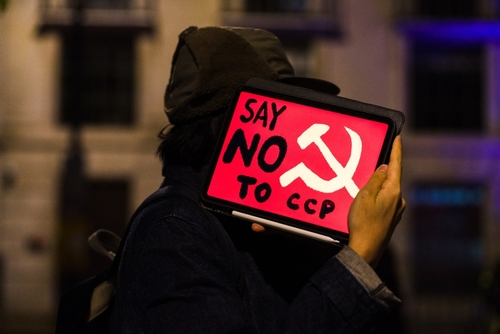 Person holding a protest sign that reads Say NO to CCP with a communist symbol