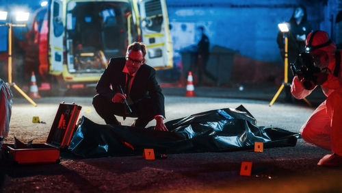 shutterstock_2230645581 Detectives investigate crime scene with body and evidence markers.