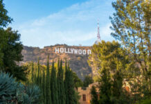 Regulators RUBBER-STAMP Hollywood MEGA-MERGER Hollywood Sign on hillside surrounded by trees, clear sky.