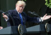Final Call Haunts Trump After Lindsey Graham’s Shock Death Man speaking at a podium, arms extended outward.