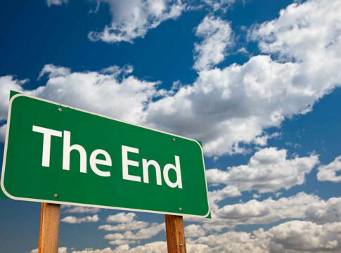 Green The End sign against cloudy blue sky.