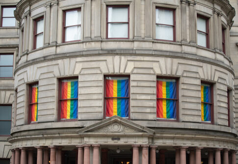 Historic building with rainbow flags displayed in the windows