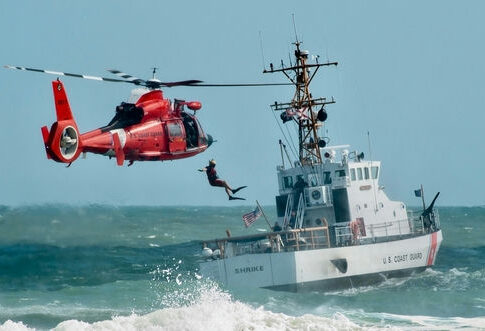 Coast Guard training with helicopter and boat in rough seas.