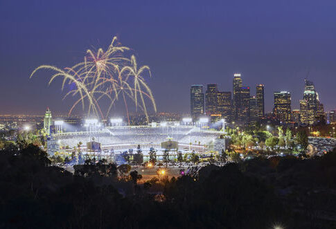Fireworks above a brightly lit stadium at night with city skyline